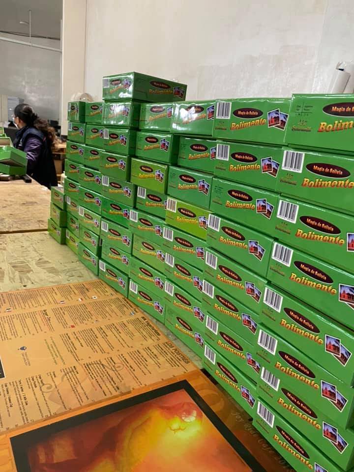 Cajas de Bolimante verdes apiladas en taller con persona
