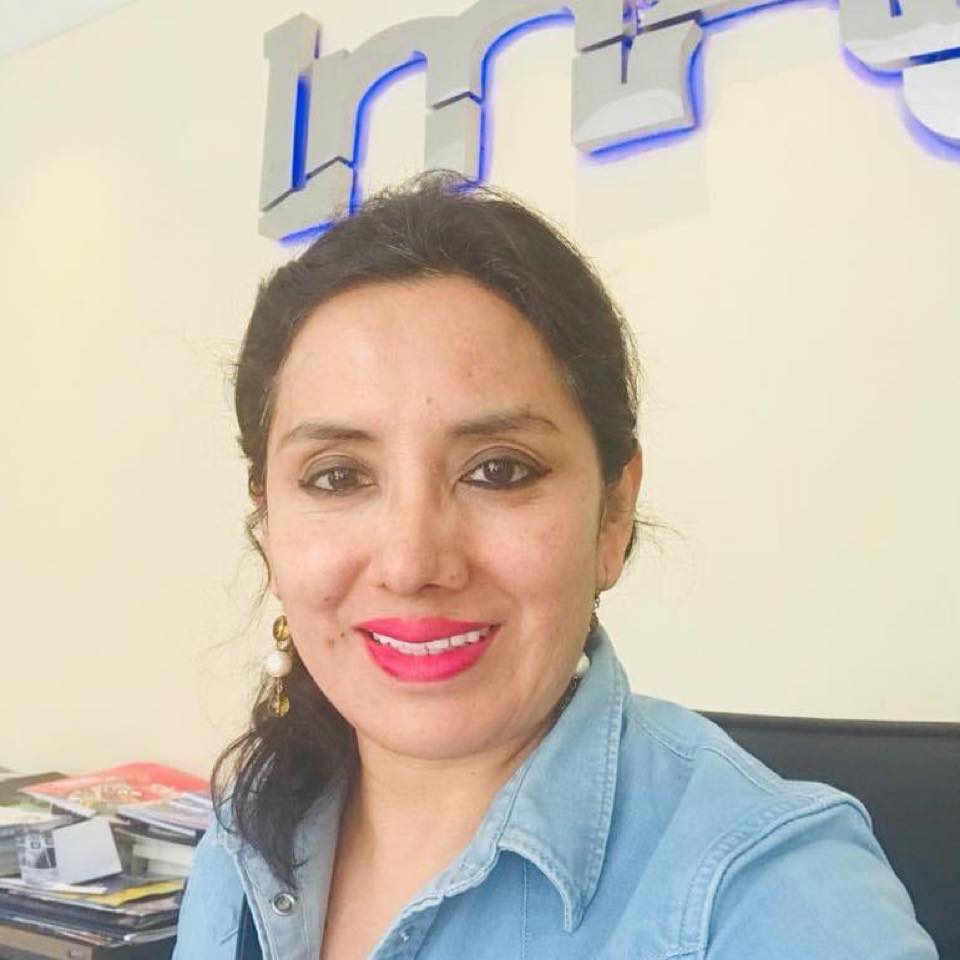 Sonia Flores, fundadora de IMAG, en la oficina delante del logo